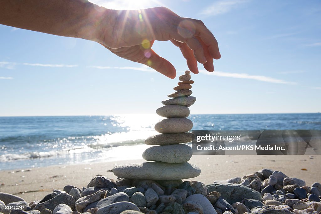 Detail of person stacking rocks at beach, sea edge