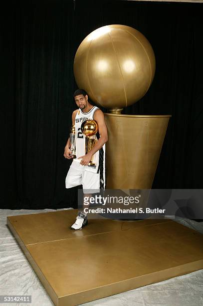 Tim Duncan of the San Antonio Spurs poses for a portrait with the Larry O'Brien Championship trophy and his 2005 Finals MVP trophy following Game...