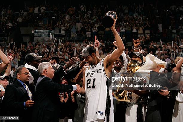 Tim Duncan of the San Antonio Spurs holds up the Finals MVP trophy as he shakes hands with NBA Commissioner David Stern following the Spurs 81-74 win...