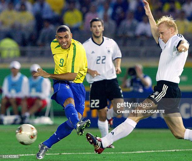 Picture taken 30 June 2002 at the International Stadium Yokohama, shows Germany's midfielder Carsten Ramelow stretching ad Brazil's forward Ronaldo...