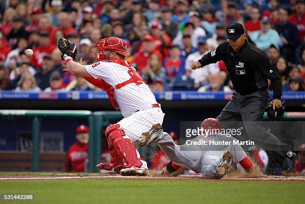 Cameron Rupp of the Philadelphia Phillies catches a throw as Zack Cozart of the Cincinnati Reds slides safely into home plate in the first inning...