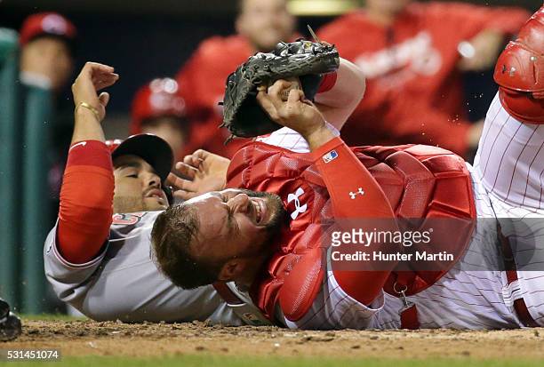 Cameron Rupp of the Philadelphia Phillies tags out Eugenio Suarez of the Cincinnati Reds during a collision at home plate in the ninth inning during...