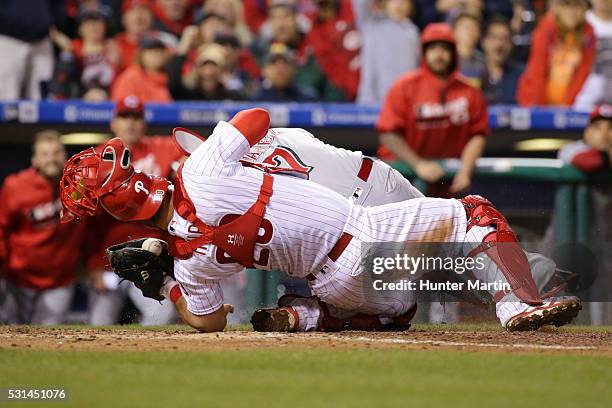 Cameron Rupp of the Philadelphia Phillies tags out Eugenio Suarez of the Cincinnati Reds during a collision at home plate in the ninth inning during...