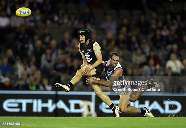 Marc Murphy of the Blues kicks whilst being tackled by Matthew Broadbent of Port Adelaide during the round eight AFL match between the Carlton Blues...