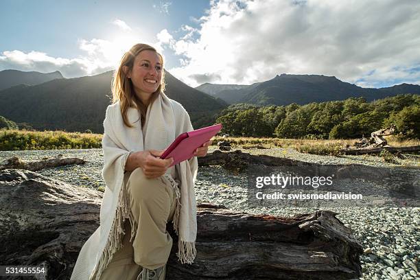 young woman sitting in nature uses a digital tablet - summer camping new zealand stock pictures, royalty-free photos & images