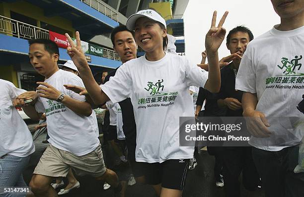 Former Olympic Women's 5000m champion Wang Junxia of China leads more than 20,000 local residents in a jogathon in the rain on June 25, 2005 in...