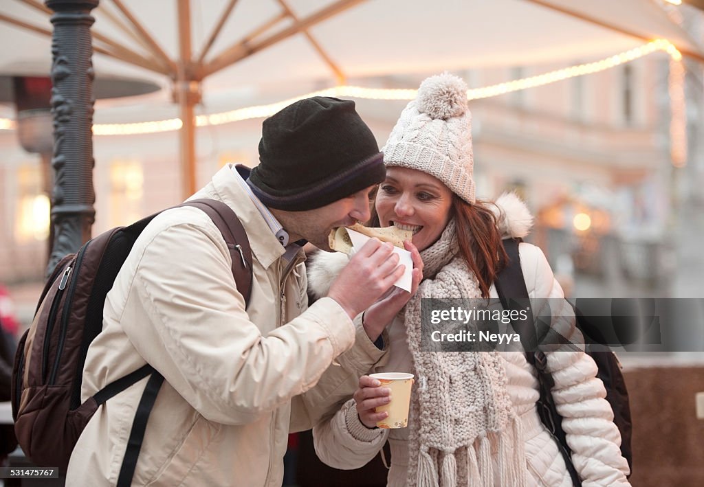 Couple dans un marché de Noël à Ljubljana manger des crêpes