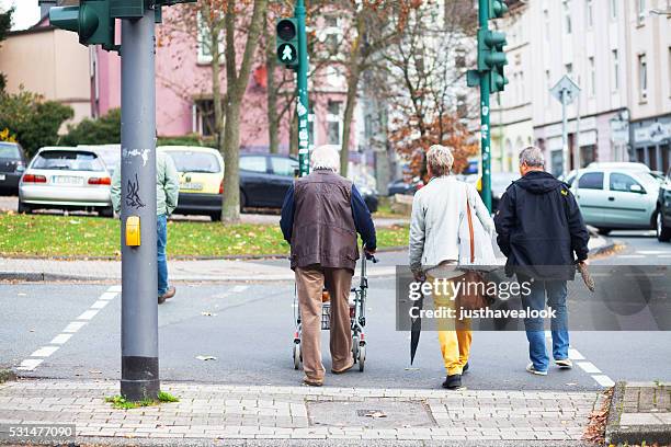 seniors crossing crosswalk - senior essen stockfoto's en -beelden