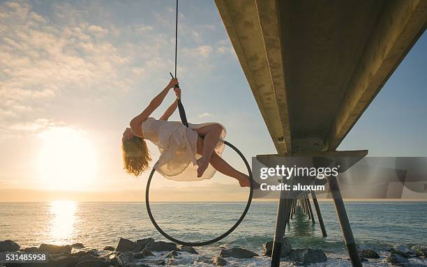 female aerial dancer at sunrise over the sea - lyra 個照片及圖片檔