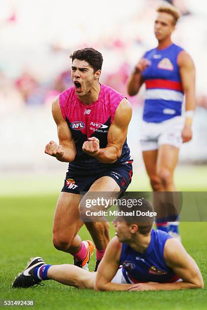 Christian Petracca of the Demons celebrates a goal above Lachie Hunter of the Bulldogs during the round eight AFL match between the Melbourne Demons...