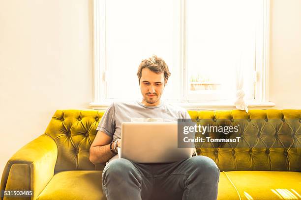 working on a sofa with a laptop on his lap - person surrounded by computer screens stock pictures, royalty-free photos & images