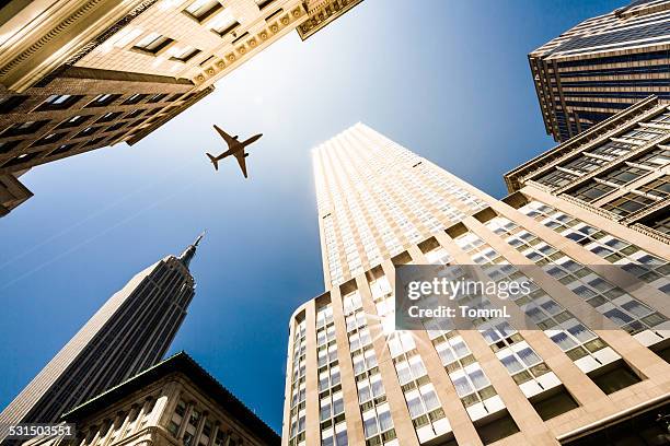 new york city, manhattan skyscraper with airplane against sun - rockefeller center stockfoto's en -beelden