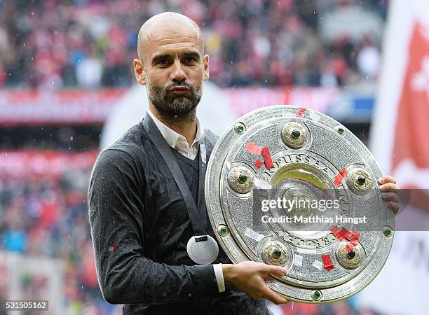 Head coach Josep Guardiola of Bayern Muenchen poses with the Meisterschale as he celebrates the Bundesliga champions after the Bundesliga match...