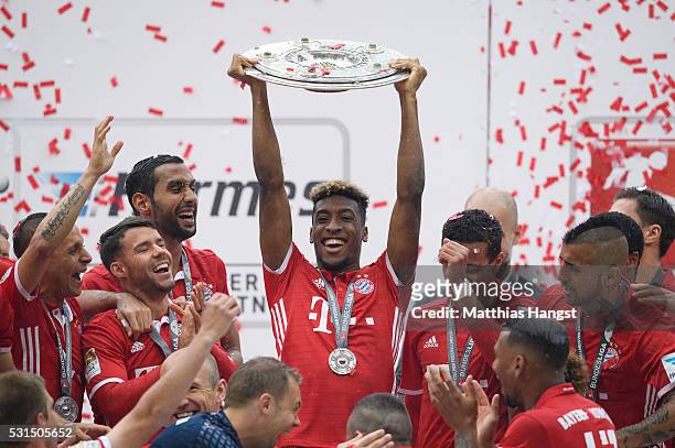 Kingsley Coman of Muenchen lifts the Meisterschale as players and staffs celebrate the Bundesliga championship after the Bundesliga match between FC...