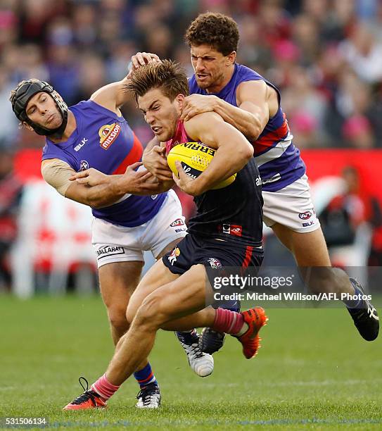 Jack Viney of the Demons fends off Caleb Daniel and Tom Liberatore of the Bulldogs during the 2016 AFL Round 08 match between the Melbourne Demons...