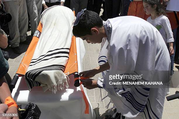 Yahel Levi ties an orange ribbon to the stretcher carrying the body of his brother Avichai Levi during his funeral in the southern West Bank...
