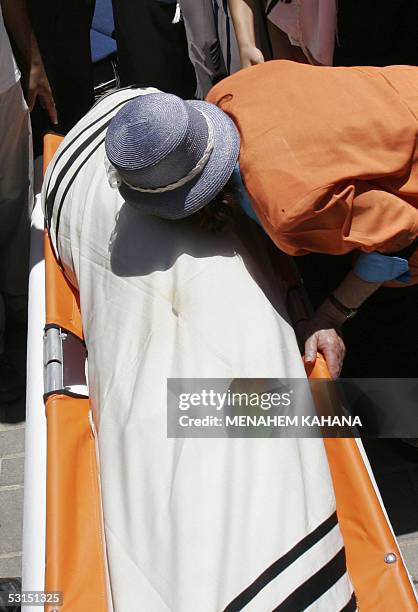The grandmother of Avichai Levi kisses her grandson body, covered with a prayer shawl, during his funeral in the southern West Bank Settlement of...