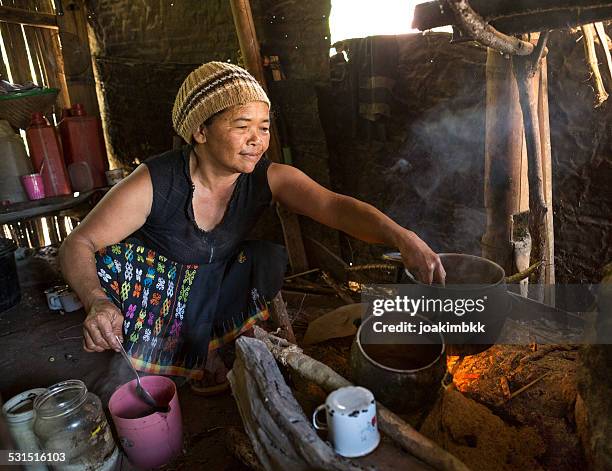senior asian lady cooking with wood fire - indonesische etniciteit stockfoto's en -beelden