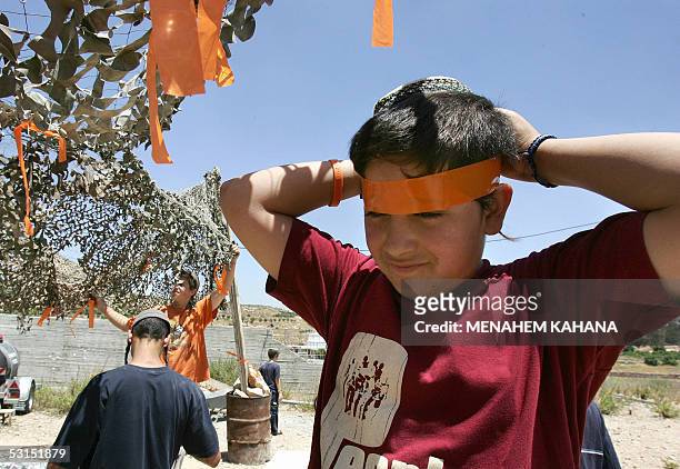 An Israeli settler ties an orange ribbon around his head at a new outpost next to Beit Hagay settlement in the West Bank 26 June 2005, as a response...