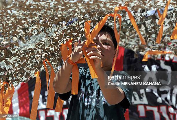 An Israeli settler ties an orange ribbon to a new outpost next to Beit Hagay settlement in the West Bank 26 June 2005, as a response to the killing...