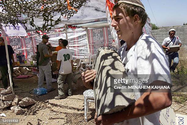 Israeli settlers carry stones as they built a new outpost next to the Beit Hagay settlement in the West Bank 26 June 2005, as a response to the...