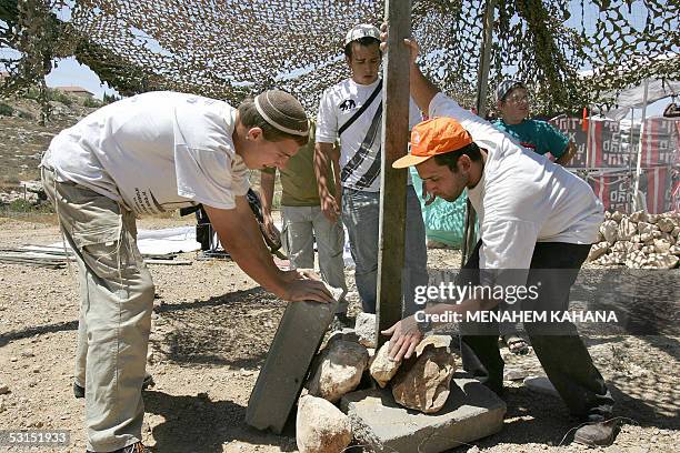 Israeli settlers carry stones as they built a new outpost next to the Beit Hagay settlement in the West Bank 26 June 2005, as a response to the...