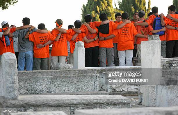 Wearing orange anti-disengagement T-shirts, friends of Avichai Levi from the southern West Bank Settlement of Beit Hagay, sing songs around his grave...