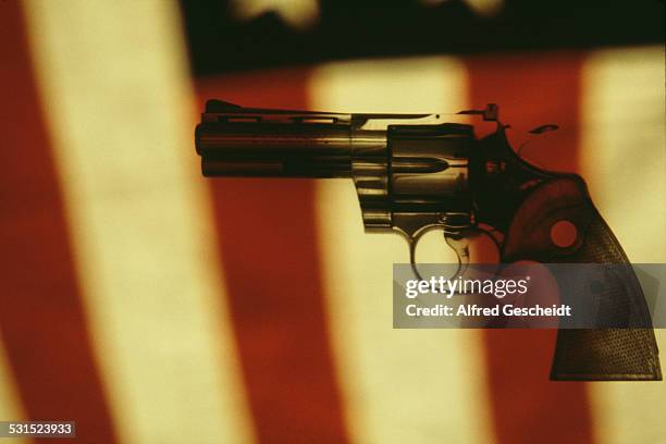 Colt Python, a .357 Magnum caliber revolver, set against the background of an American flag, 1982.