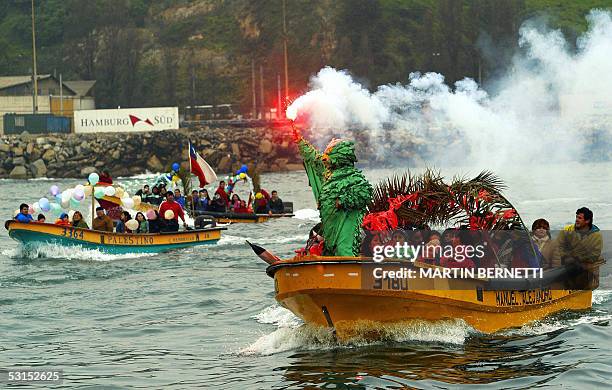 Un pescador artesanal con disfraz tradicional prende una bengala durante la procesion de la imagen de San Pedro , llevada en otra lancha pesquera, en...