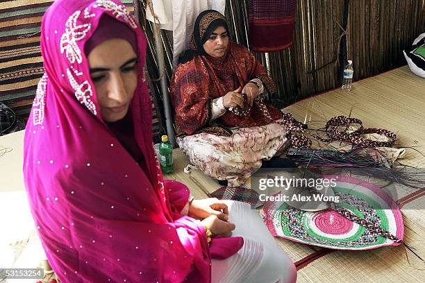 Omani Maryam Al-Shehhi weaves a basket as Khalsa Al-Jabri looks during the 39th annual Smithsonian Folklife Festival at the National Mall on June 26,...