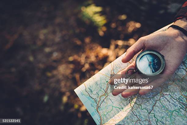 teenager-mädchen mit kompass lesen der karte im wald - navigationsinstrument stock-fotos und bilder