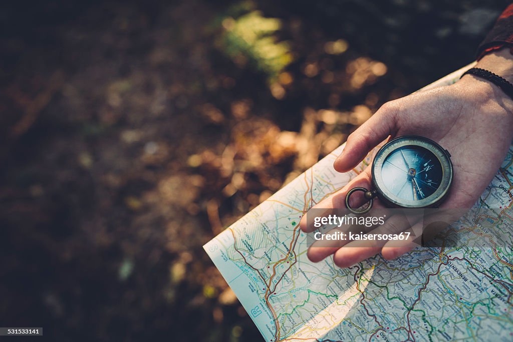 Teenager girl with Compass Reading a Map in the forest