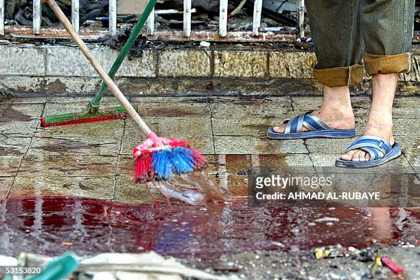 Iraqis clean blood outside a barber shop in the bustling district of Baghdad Al-Jadida in the Iraqi war-torn capital, 27 June 2005. Three people were...