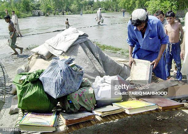An Afghan refugee salvages his belongings from his flood affected camp in Khazana, some 20 kms from Peshawar, 27 June 2005. Following the flash...