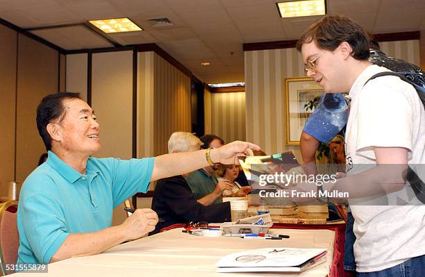 George Takei signs autographs for fans.