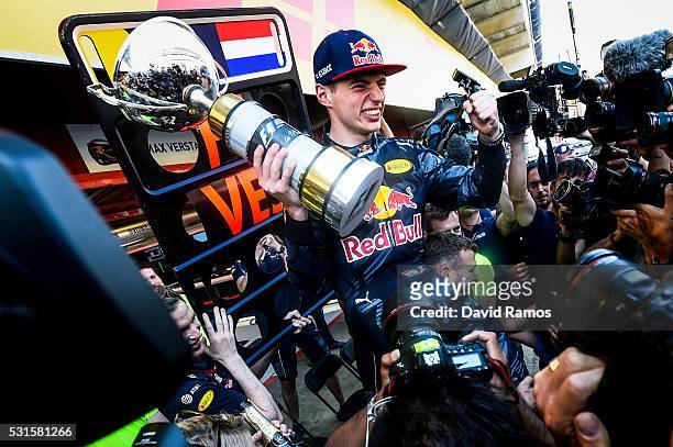 Max Verstappen of Netherlands and Red Bull Racing celebrates with the team in the pit lane after winning his first F1 race at the Spanish Formula One...