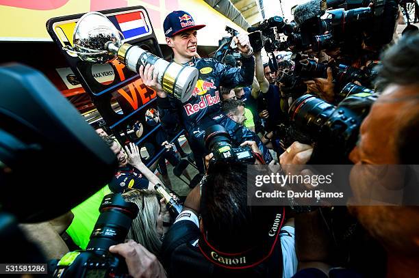 Max Verstappen of Netherlands and Red Bull Racing celebrates with the team in the pit lane after winning his first F1 race at the Spanish Formula One...