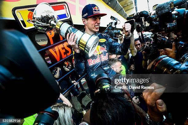 Max Verstappen of Netherlands and Red Bull Racing celebrates with the team in the pit lane after winning his first F1 race at the Spanish Formula One...