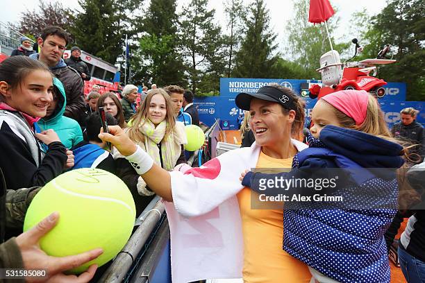 Tatjana Maria of Germany signs autographs with her daughter Charlotte after defeating Antonia lottner of Germany during Day Two of the Nuernberger...