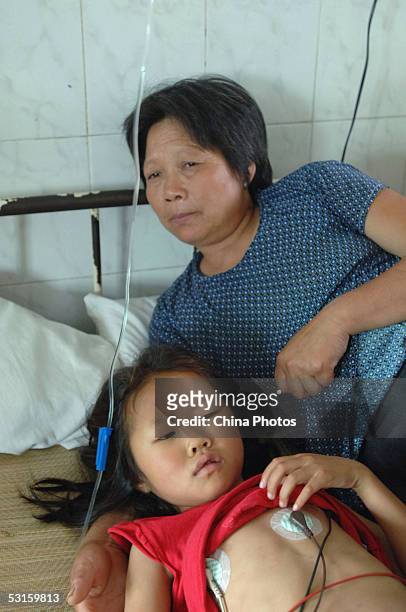 Young girl sickened during a vaccine accident undergoes treatment as her grandmother attends to her at a local hospital on June 28, 2005 in Sixian...