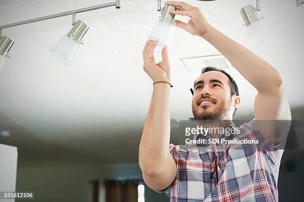 man installs light fixture in new home - household fixture stock pictures, royalty-free photos & images