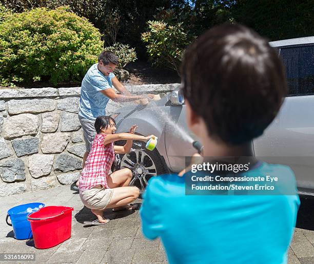 family getting sprayed washing car - car splashing water on people stock pictures, royalty-free photos & images