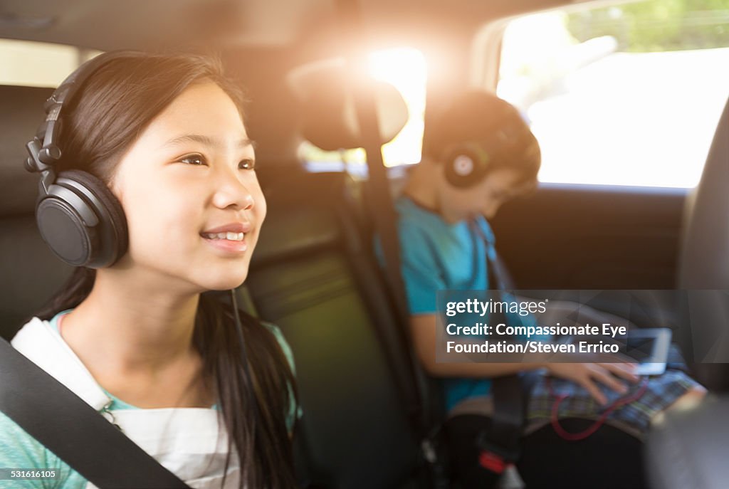 Brother and sister listening to headphones in car