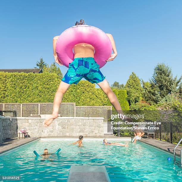 teenager jumping into pool with rubber ring - zwembroek stockfoto's en -beelden