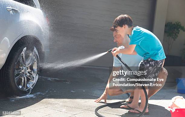 father and son washing car together - car splashing water on people stock pictures, royalty-free photos & images