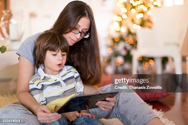 small boy with his mother using a digital tablet - boy in pajamas and mom on tablet stock-fotos und bilder