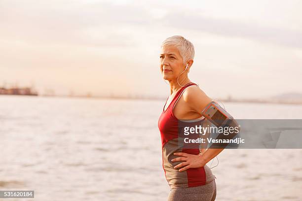 mature-senior woman jogging beside the sea - old woman running stock pictures, royalty-free photos & images