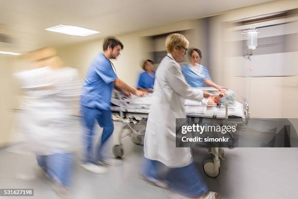 doctor wheeling patient - person in emergency hospital stockfoto's en -beelden