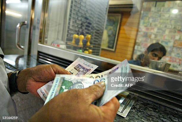 Customer counts Malaysian ringgit bills at a currency exchange counter in Kuala Lumpur, 29 June 2005. The executive director of the Malaysian...