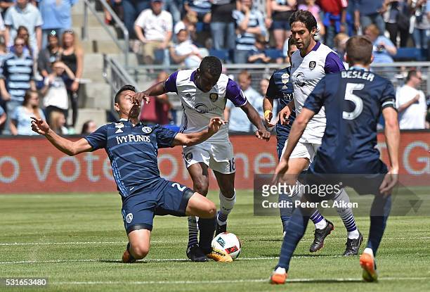 Mid-fielder Roger Espinoza of Sporting Kansas City gets pushed to the ground by defender Kevin Molino of Orlando City SC during the first half on May...